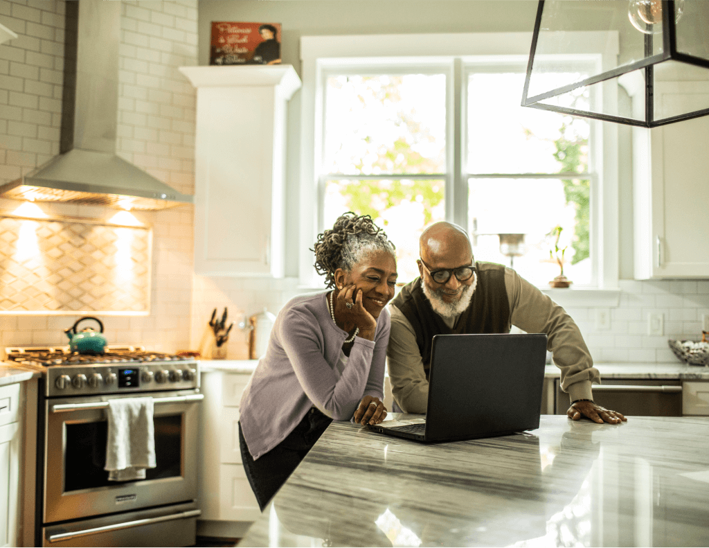Couple in kitchen looking at laptop