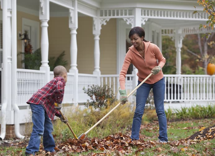 Mother and son raking leaves in front of their home