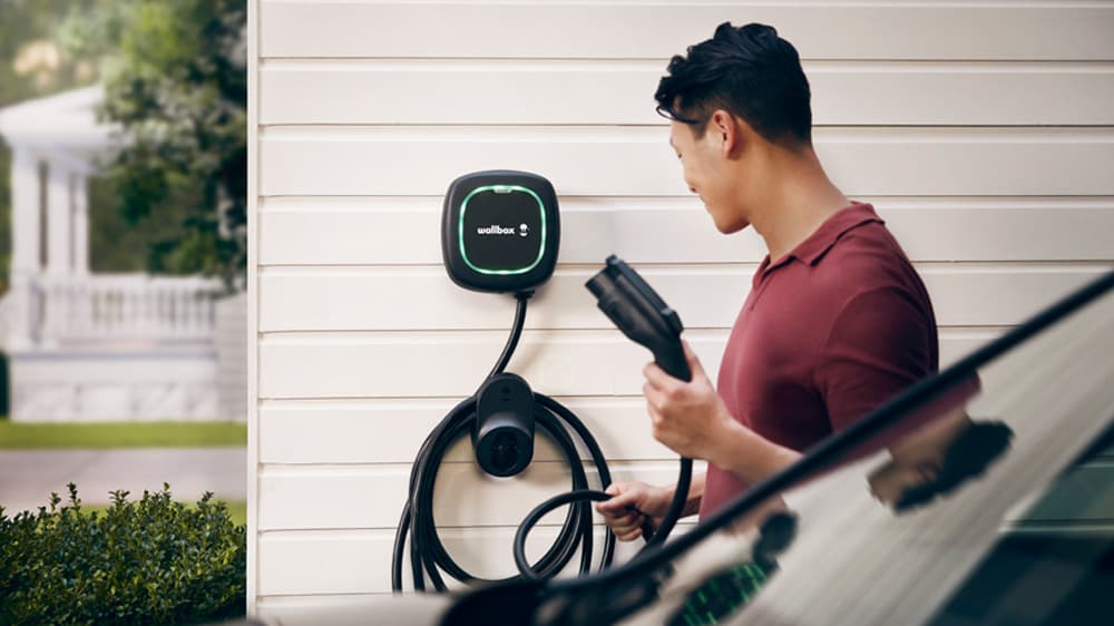 Man using a Wallbox unit to charge his electric vehicle.