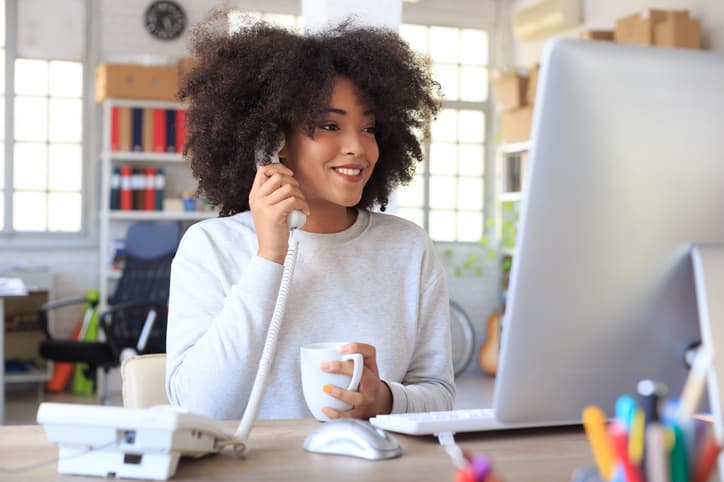 Young business woman working from home while using a phone